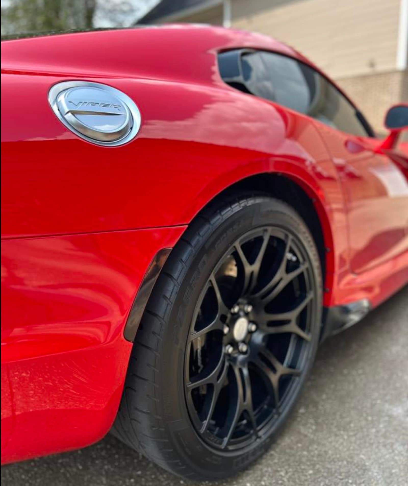 Detailed black wheel and rear quarter panel on a red Viper after an exterior detail